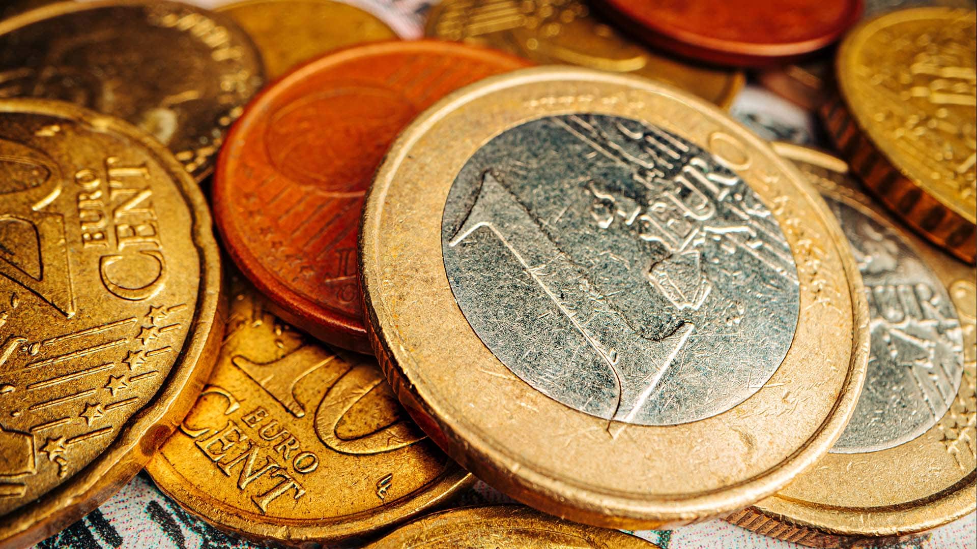 Pièces de monnaie en euros et centimes suisses empilées, montrant des pièces de 1 euro bimétal au premier plan
