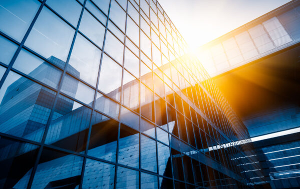 Immeuble de verre moderne avec façade transparente et soleil couchant, symbolisant la finance et le change CHF/EUR