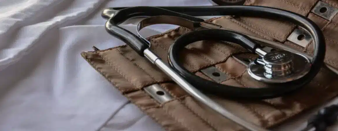 Stéthoscope médical noir et argent posé sur tissu beige avec fond blanc