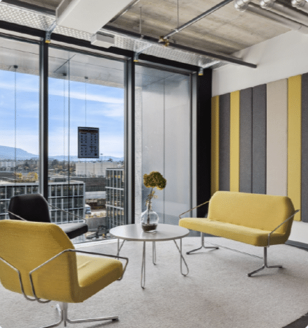 Bureau moderne avec vue panoramique sur les montagnes, mobilier jaune et gris, baies vitrées
