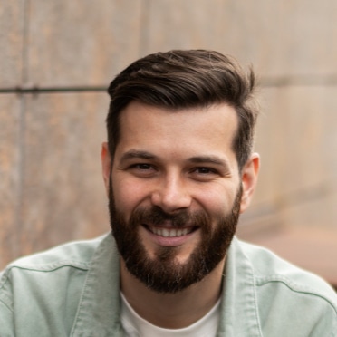 Homme souriant portant une chemise grise clair, représentant un client satisfait de b-sharpe.io