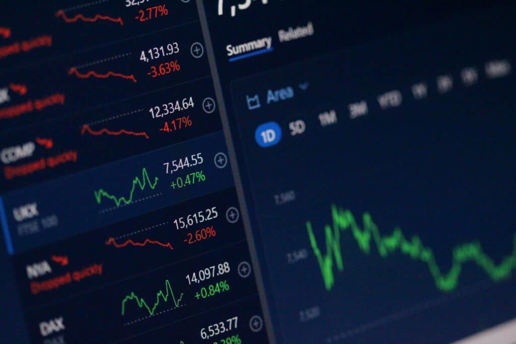 Tableau de bord financier affichant des indices boursiers avec variations en rouge et vert, prix et graphiques de tendances